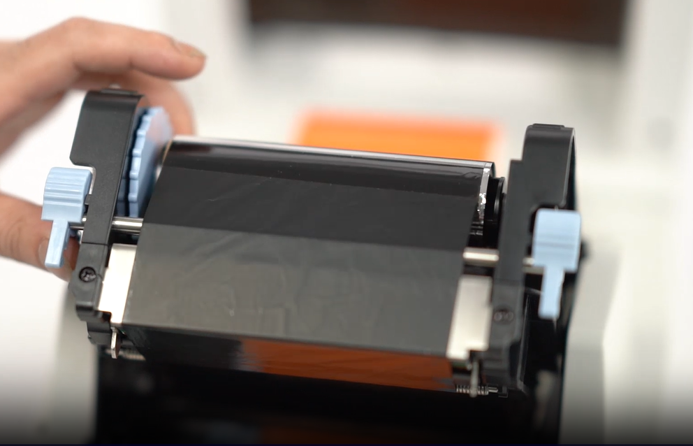 Close-up of a thermal transfer ribbon being installed in a printer.